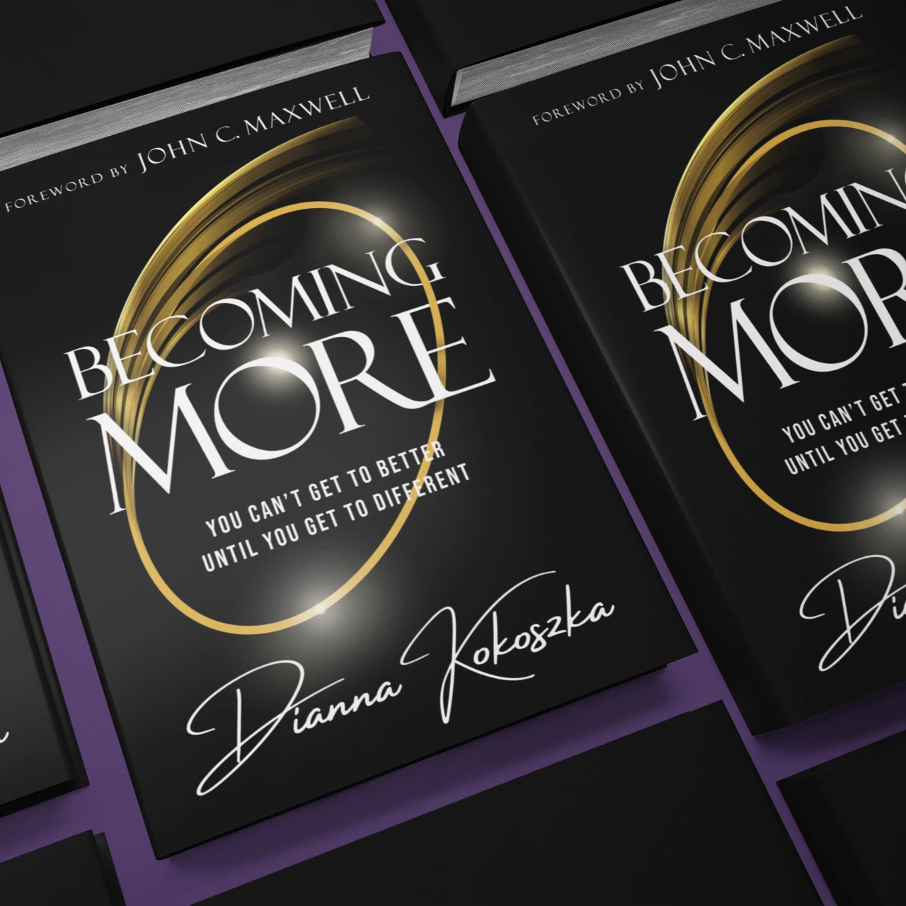 Two copies of the book Becoming More, black covers with a gold ring, laid at an angle on a royal purple surface